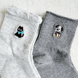 Set of two crew-length socks featuring playful cat and dog designs on a soft fabric. Each pair showcases a different animal-themed design with charming expressions and subtle color, adding a whimsical and cozy touch to everyday outfits.