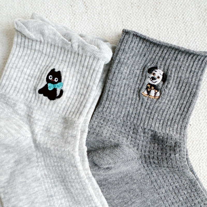 Set of two crew-length socks featuring playful cat and dog designs on a soft fabric. Each pair showcases a different animal-themed design with charming expressions and subtle color, adding a whimsical and cozy touch to everyday outfits.