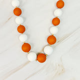 Necklace with orange and white beads on a light background
