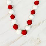 Necklace with red and white beads on a light wooden surface