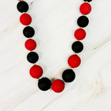 Necklace with red and black beads on a white wooden surface