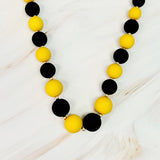 Necklace with black and yellow beads on a light wooden surface