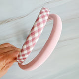 A set of padded fabric headbands in assorted pastel and plaid designs, including soft pink, green tones. Each headband features a cushioned, textured surface that blends solid and patterned fabrics for a stylish, comfortable everyday accessory.