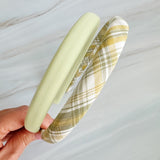 A set of padded fabric headbands in assorted pastel and plaid designs, including soft pink, green tones. Each headband features a cushioned, textured surface that blends solid and patterned fabrics for a stylish, comfortable everyday accessory.