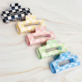Set of colorful checkered hair clips on a light wooden surface