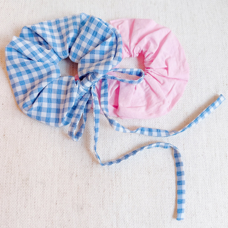 Set of two hair scrunchies featuring bold checkered patterns with elegant trailing ribbons—perfect for adding a playful yet polished touch to any hairstyle.