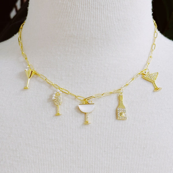 Gold-tone necklace featuring multiple celebratory charms including a champagne bottle, a drinking glass, and, arranged in a layered style for a fun and festive look.