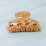 A set of two hair claws featuring a row of vibrant red cherry designs, adding a playful and fruity touch to any hairstyle.