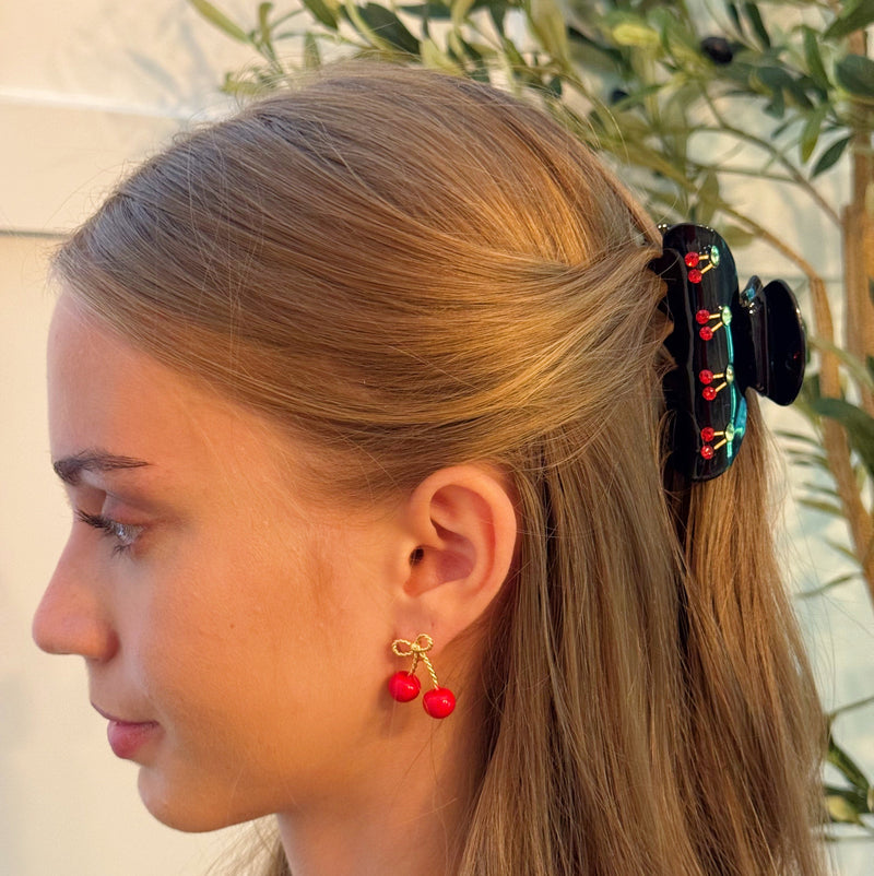 A set of two hair claws featuring a row of vibrant red cherry designs, adding a playful and fruity touch to any hairstyle.