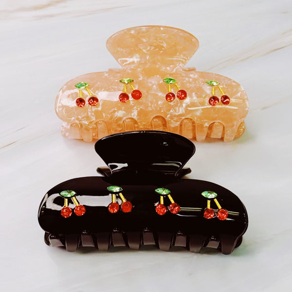 A set of two hair claws featuring a row of vibrant red cherry designs, adding a playful and fruity touch to any hairstyle.