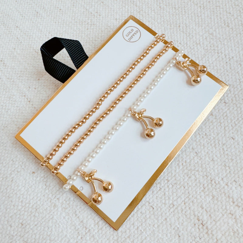  Set of three stretch bracelets adorned with dangling cherry charms—adding a sweet and playful flair to your accessory collection.