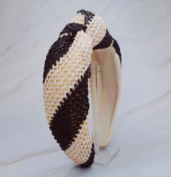 Knotted headband with bold black stripes on a beige background for a chic and modern look.