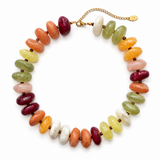 A multicolor beaded necklace made of polished oval gemstone beads in shades of orange, green, pink, white, and deep red, strung on a gold chain with a small gold tag.