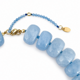 Blue beaded bracelet with gold clasp on a white background