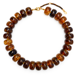 A beaded necklace made of polished amber-brown disc beads with a small gold clasp and extender chain, photographed on a clean white background.
