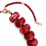 Red beaded bracelet with gold accents on a white background