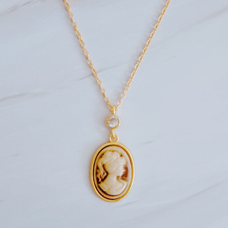 Classic gold chain necklace featuring a vintage-inspired cameo pendant with an ornate gold-tone frame and adjustable clasp closure.