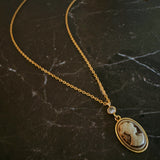 Classic gold chain necklace featuring a vintage-inspired cameo pendant with an ornate gold-tone frame and adjustable clasp closure.