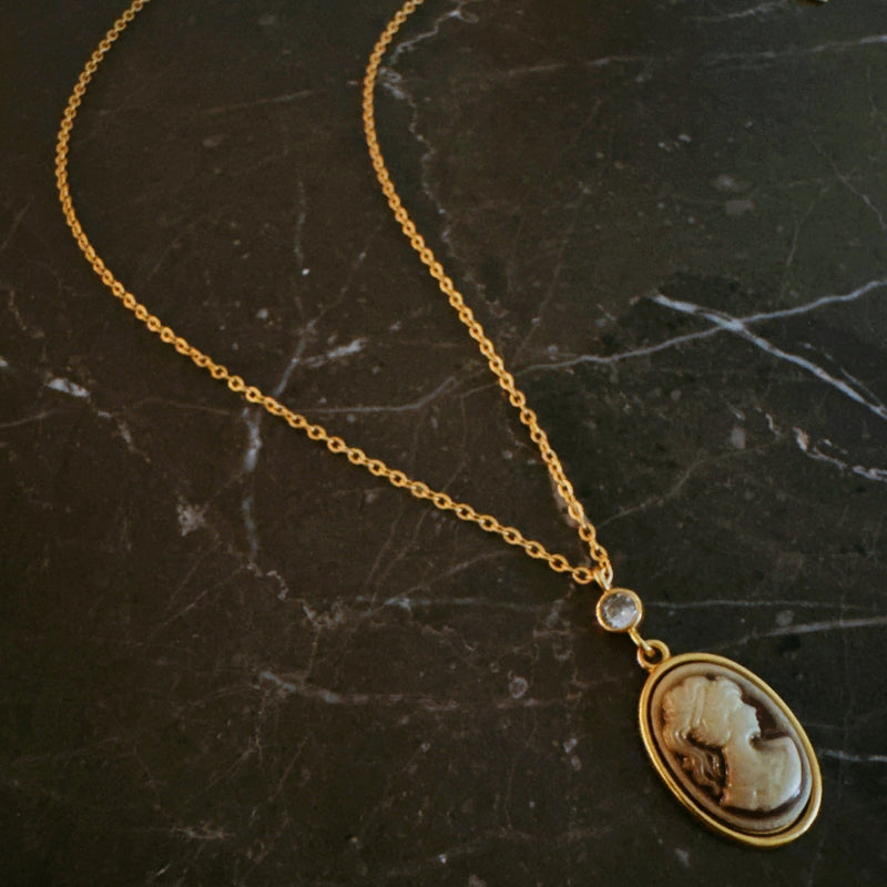 Classic gold chain necklace featuring a vintage-inspired cameo pendant with an ornate gold-tone frame and adjustable clasp closure.