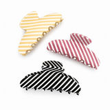Three striped hair clips in yellow, red, and black on a white background