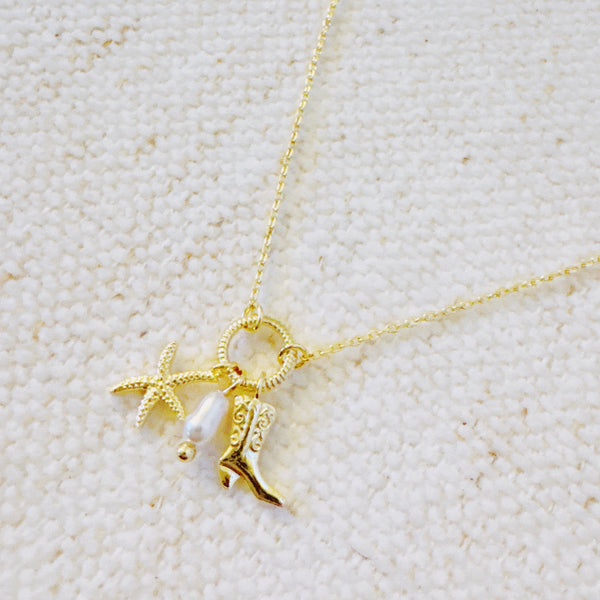 Gold-tone chain necklace adorned with a starfish charm and a western boot charm, capturing a playful blend of coastal and cowgirl vibes.