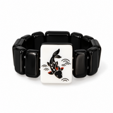 A black beaded bracelet with a central square white panel featuring a black koi fish design with red and orange accents, set against a plain white background.