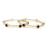 Gold bangles with black stones on a white background