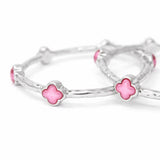 Silver bracelet with pink clover-shaped charms on a white background