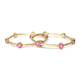 Gold bangles with pink stones on a white background