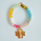 Colorful beaded stretch bracelet featuring a radiant gold-tone clover charm with an engraved initial at the center. The bracelet combines vibrant multicolored beads with a polished gold accent, creating a cheerful and personalized accessory perfect for layering or gifting.