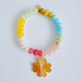 Colorful beaded stretch bracelet featuring a radiant gold-tone clover charm with an engraved initial at the center. The bracelet combines vibrant multicolored beads with a polished gold accent, creating a cheerful and personalized accessory perfect for layering or gifting.