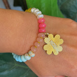 Colorful beaded stretch bracelet featuring a radiant gold-tone clover charm with an engraved initial at the center. The bracelet combines vibrant multicolored beads with a polished gold accent, creating a cheerful and personalized accessory perfect for layering or gifting.
