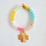 Colorful beaded stretch bracelet featuring a radiant gold-tone clover charm with an engraved initial at the center. The bracelet combines vibrant multicolored beads with a polished gold accent, creating a cheerful and personalized accessory perfect for layering or gifting.