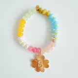 Colorful beaded stretch bracelet featuring a radiant gold-tone clover charm with an engraved initial at the center. The bracelet combines vibrant multicolored beads with a polished gold accent, creating a cheerful and personalized accessory perfect for layering or gifting.