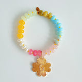 Colorful beaded stretch bracelet featuring a radiant gold-tone clover charm with an engraved initial at the center. The bracelet combines vibrant multicolored beads with a polished gold accent, creating a cheerful and personalized accessory perfect for layering or gifting.