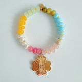 Colorful beaded stretch bracelet featuring a radiant gold-tone clover charm with an engraved initial at the center. The bracelet combines vibrant multicolored beads with a polished gold accent, creating a cheerful and personalized accessory perfect for layering or gifting.