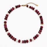A beaded necklace featuring alternating dark red polished beads and white baroque pearls, accented with small gold spacer rings and a gold clasp with extender chain, shown on a plain white background.