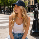 A woman wearing a colorful beaded necklace and a ball cap on the street