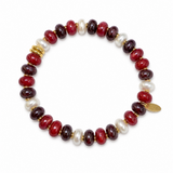 A beaded stretch bracelet featuring glossy oval beads in deep red, dark burgundy, white, and gold spacer rings, with a small gold tag on the right side, set against a plain white background.