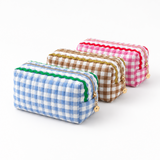 blue, pink, brown gingham fabric with colorful wavy details on top lined up, white background