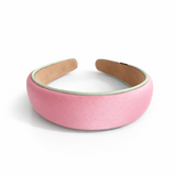 A softly padded wide headband in a solid hue, finished with a distinct contrast border trim along the edges, offering a chic and polished look for everyday wear.