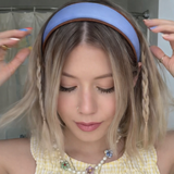 A softly padded wide headband in a solid hue, finished with a distinct contrast border trim along the edges, offering a chic and polished look for everyday wear.