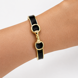 Gold and black bracelet on a wrist against a light background