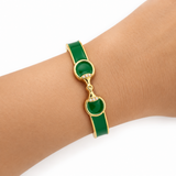 Green bracelet with gold accents on a wrist against a white background
