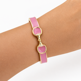 Pink bracelet with gold accents on a wrist against a white background