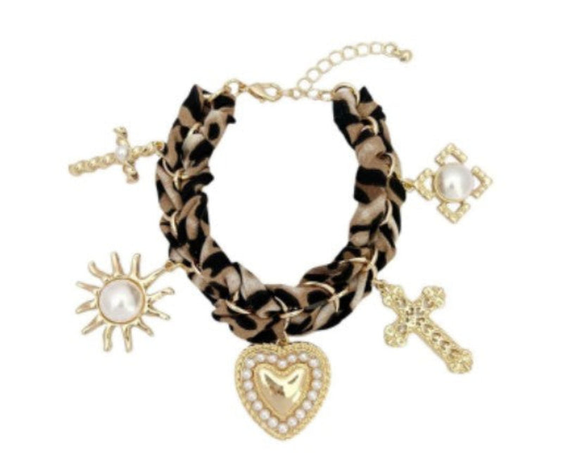 Gold-tone charm bracelet with a leopard-print scarf wrap, featuring dangling heart, cross, sun, and pearl-accented charms.
