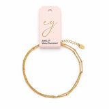 Gold anklet on a white background with a pink card displaying 'ey' branding.