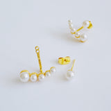 Gold-tone earrings featuring a modern double-piece design with smooth pearl accents. The front and back components create a dimensional, elegant arc that frames the earlobe beautifully.