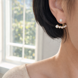 Gold-tone earrings featuring a modern double-piece design with smooth pearl accents. The front and back components create a dimensional, elegant arc that frames the earlobe beautifully.