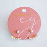 Gold-tone earrings featuring a modern double-piece design with smooth pearl accents. The front and back components create a dimensional, elegant arc that frames the earlobe beautifully.